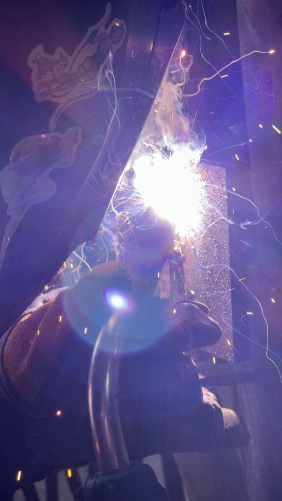 a 3G plate test. welded uphill in the vertical position. In this image he is using the SMAW (Stick) welding process. He is using an E7018 1/8" electrode